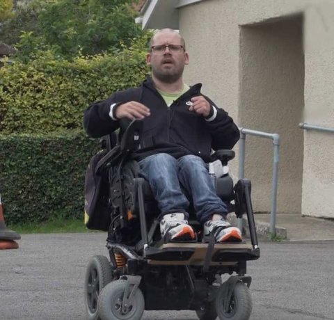 Our wheelchair skills trainer in his powered chair outside a single story building