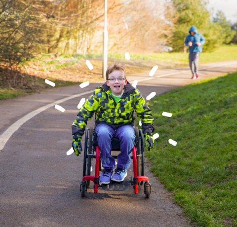 A young wheelchair user pushed himself down a pathway