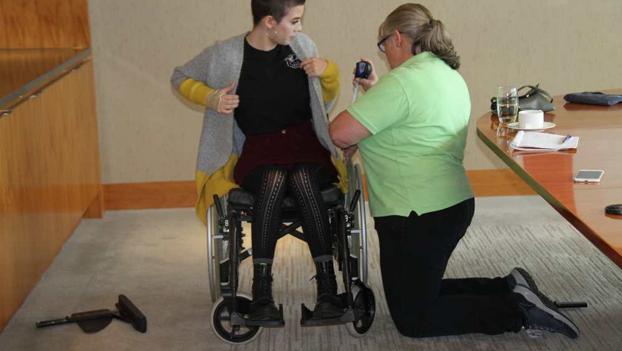Millie Rose being measured by a Whizz Kidz clinician in her wheelchair