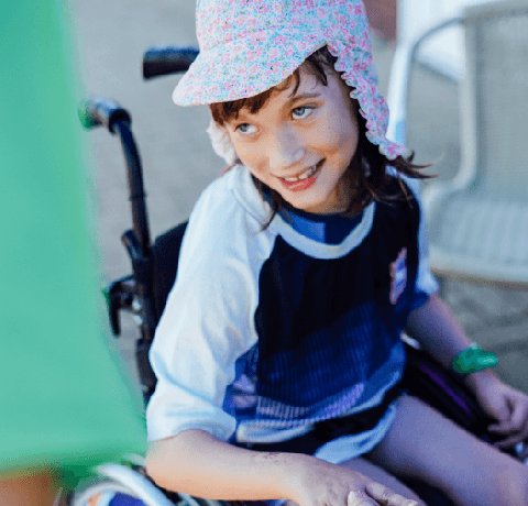 A young wheelchair user smiles in their manual chair