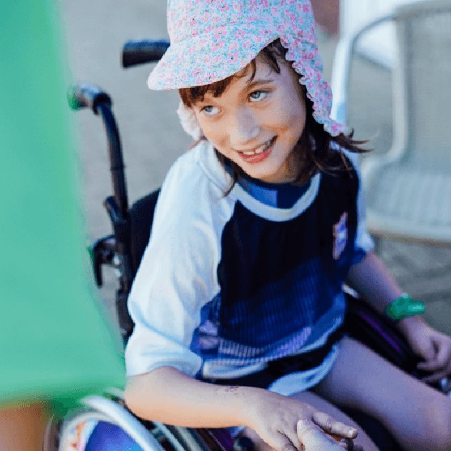 A young wheelchair user smiles in their manual chair