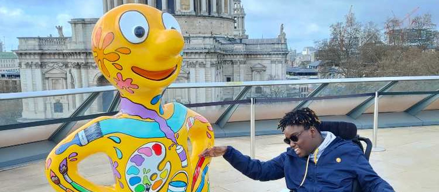 Kashyani sits in their powered chair next to Morph with St Pauls in the background