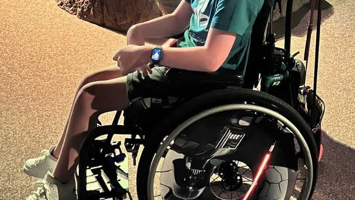 Zach in his black wheelchair on a mini-gold course
