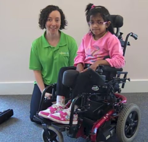 A Whizz Kidz staff member with a young wheelchair user in her super cool powered chair