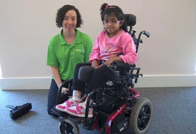 A Whizz Kidz staff member with a young wheelchair user in her super cool powered chair