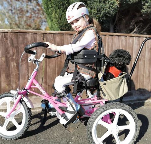 Carmella smiles as she uses her awesome pink trike with her dog, Tinker in the basket