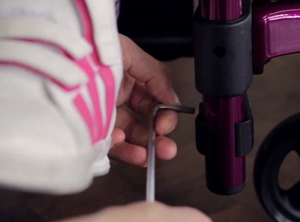 A manual wheelchair being adjusted with an allen key