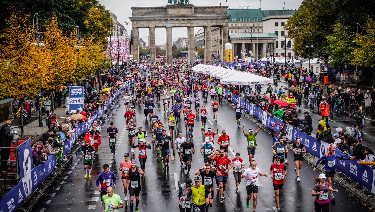 A group of runners running in front of the Brandenburg Gate