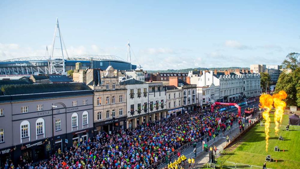 A mass of runners run through Cardiff with the Millennium Stadium in the background