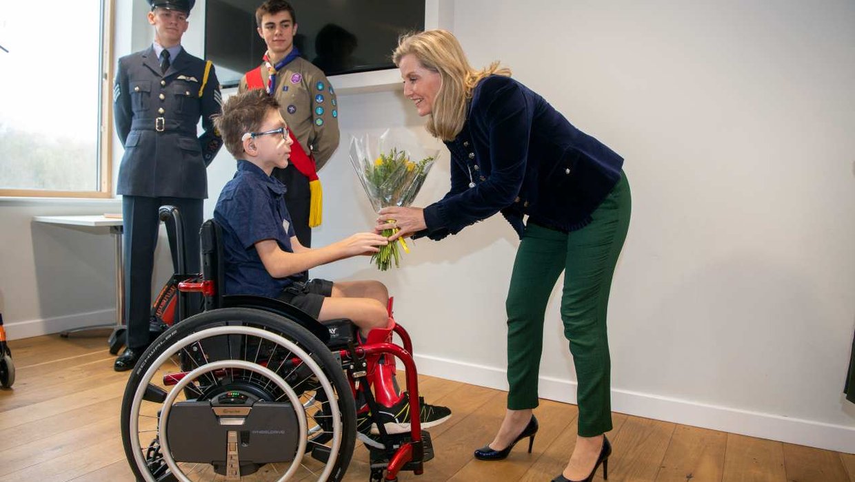 HRH presenting a young wheelchair user with a bunch of flowers