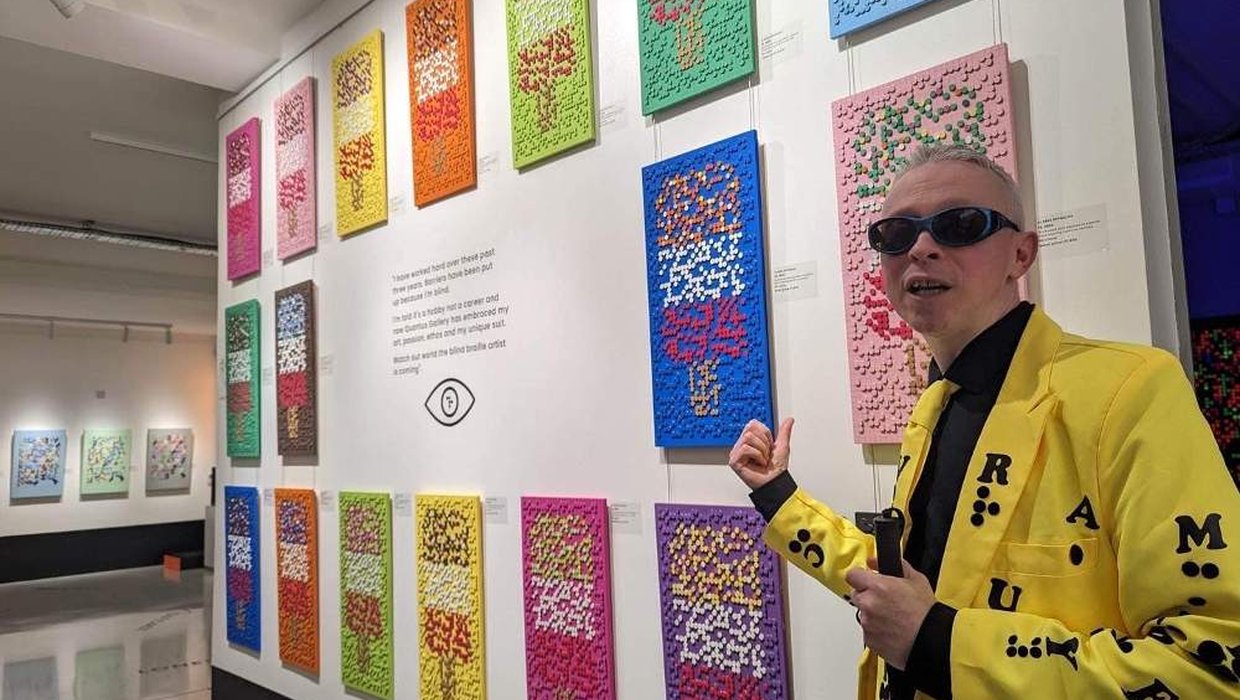 Clarke Reynolds in front of his brail exhibition